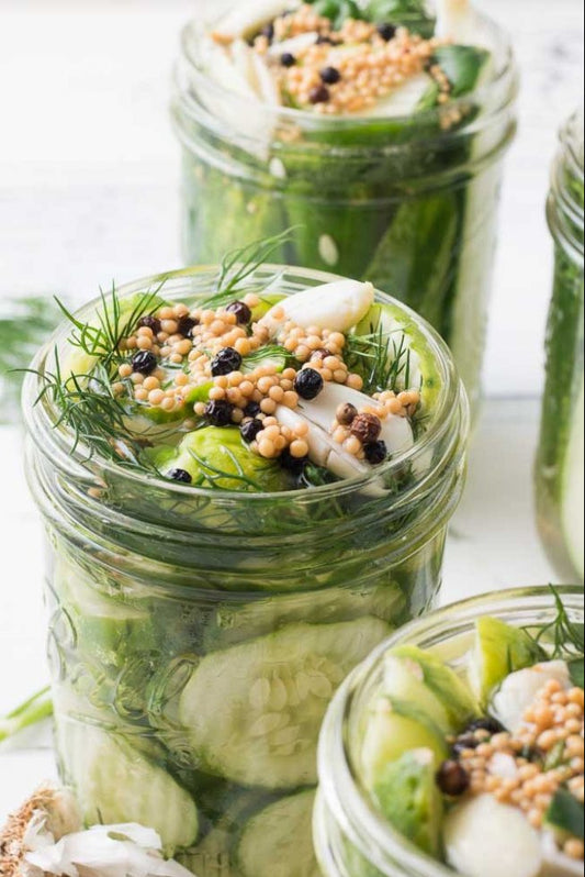 Three jars of pickled vegetables with herbs and spices on a white background